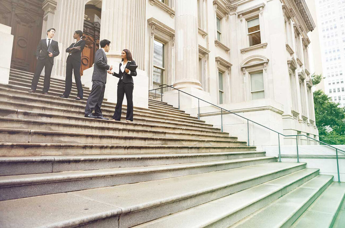A group of government contracting business owners are standing on a set of stairs while talking to each other.